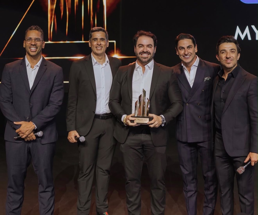 Ronaldo Dantas com o troféu do Real Estate Awards 2026, ao lado dos apresentadores